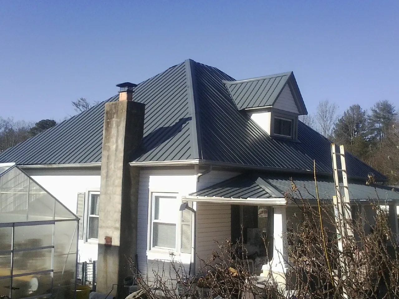 Dark blue standing seam metal roof on a white farmhouse with dormer — Slate & Tile Roof Repair by Roofing Brothers in Lawnside