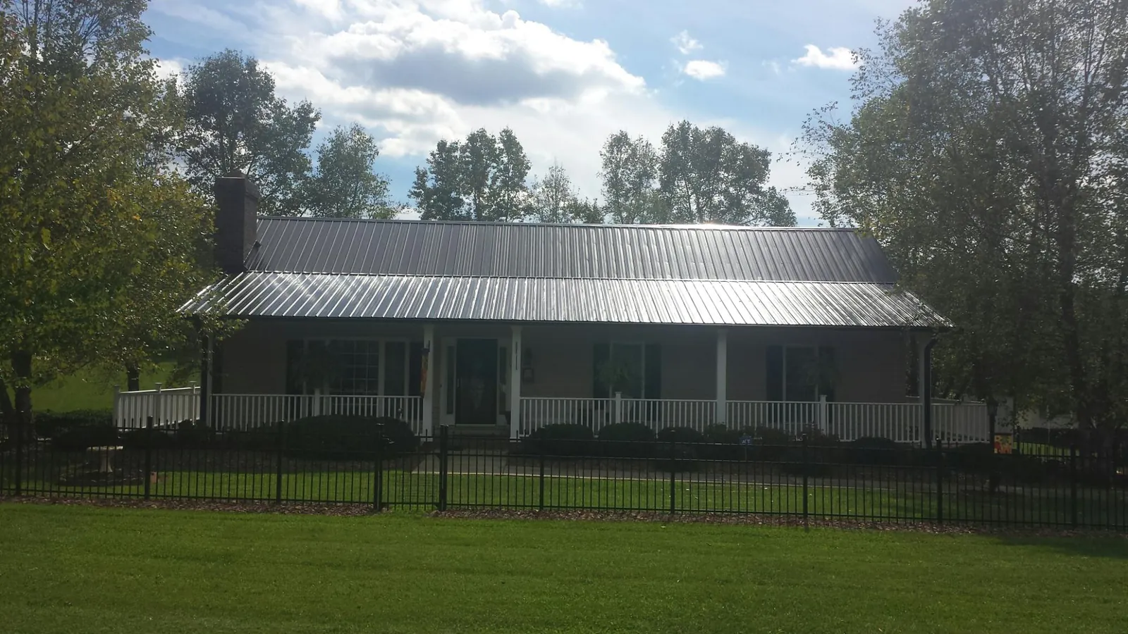 Gray metal roof on a brick ranch with a full width front porch — Gutter Guard Installation work by our crew in Lawnside
