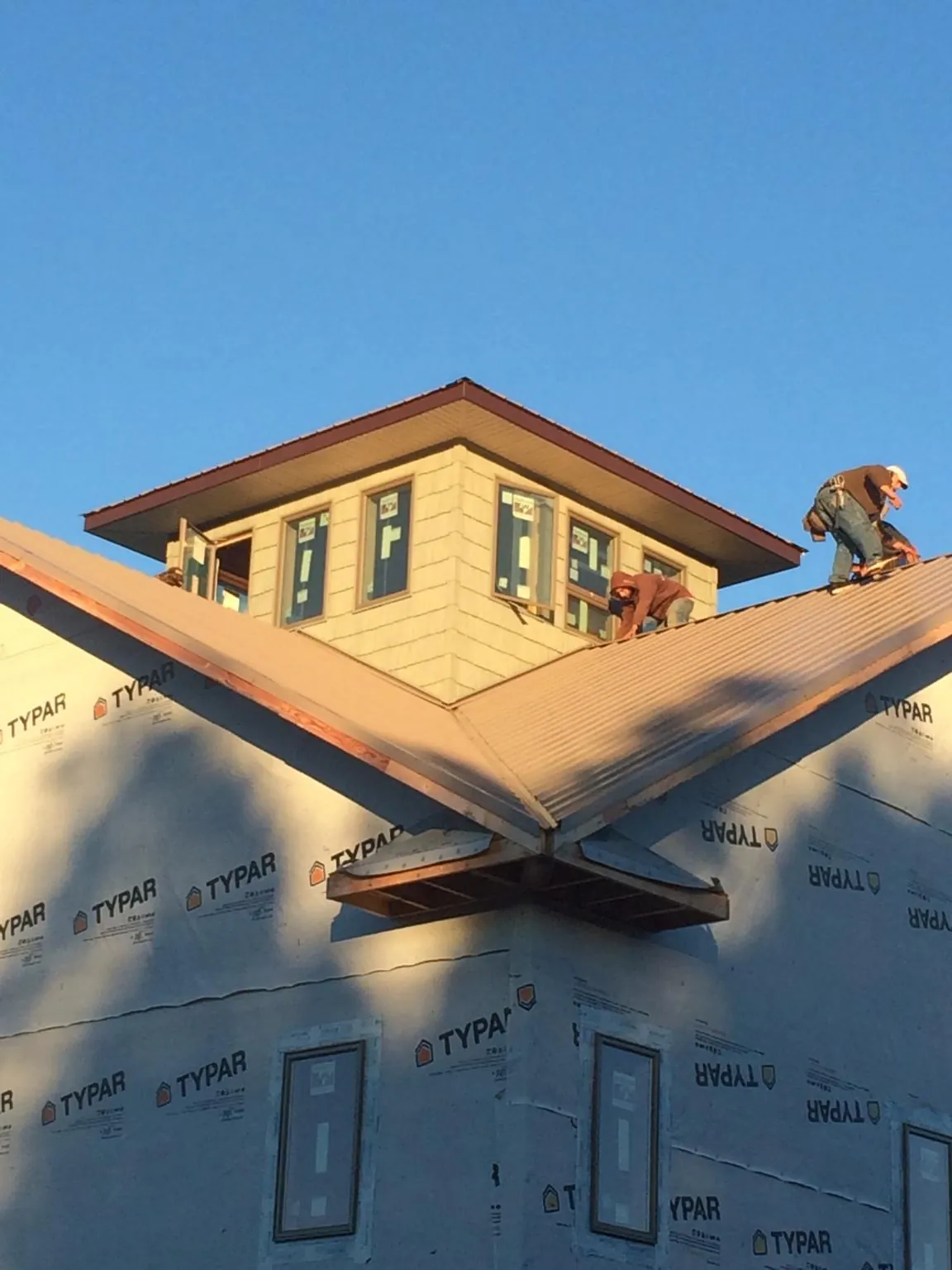 Roofers working around a rooftop cupola on a new metal roof at sunset — Roof Waterproofing in Lawnside by Roofing Brothers